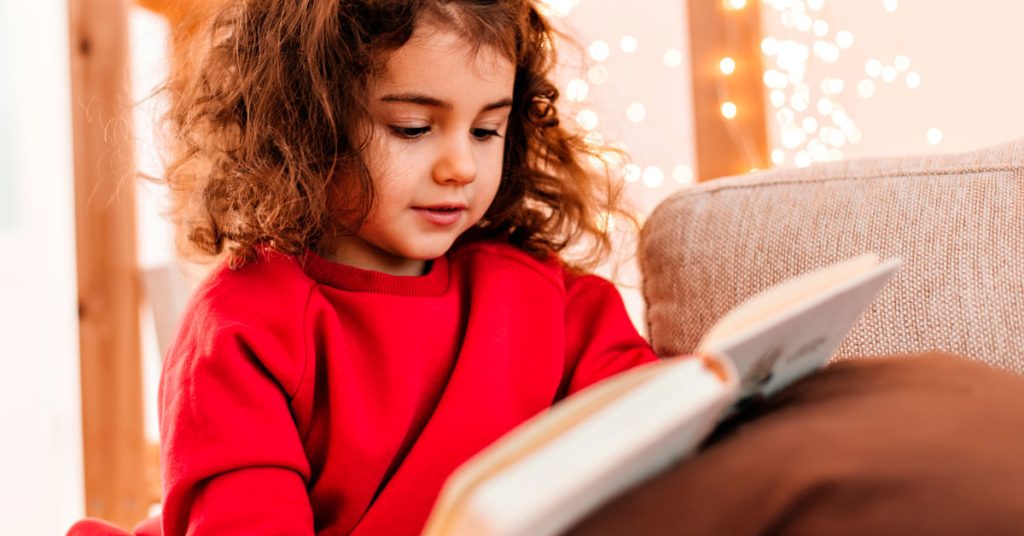 Niña leyendo un libro en inglés al aire libre