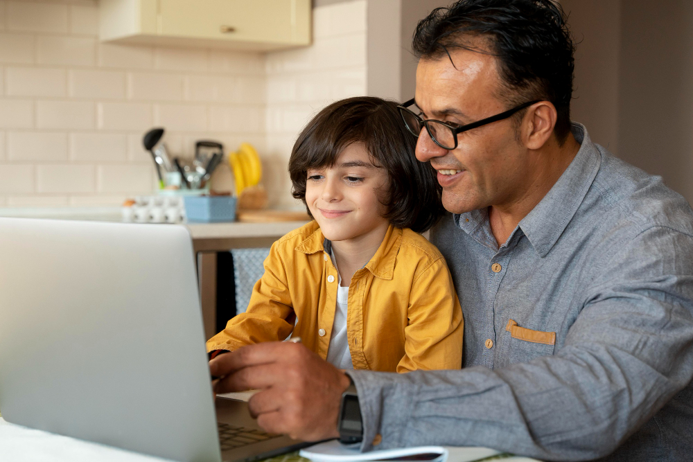 Padre e hijo sonriendo mientras ven la clase de inglés juntos en la laptop.