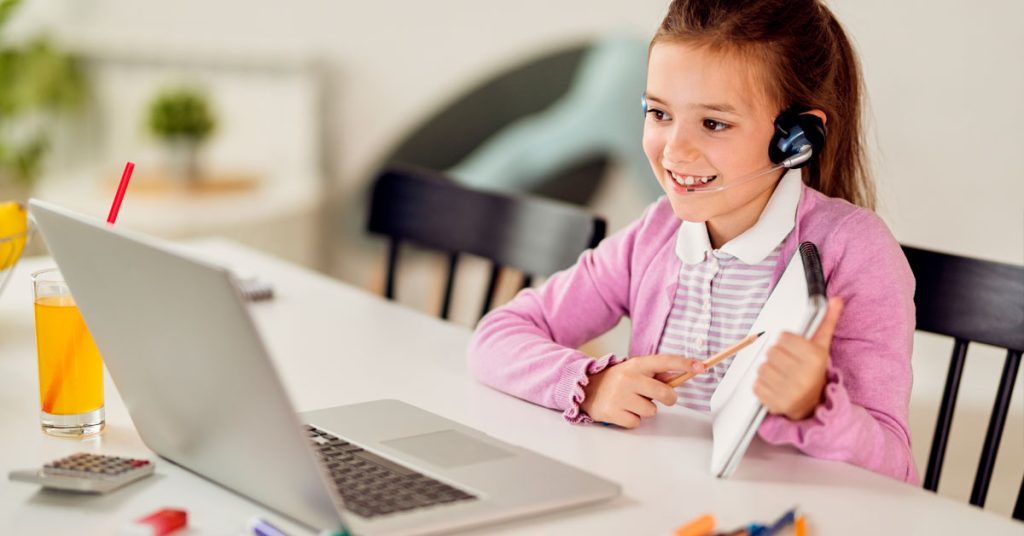 Niña escribiendo en un cuaderno mientras aprende inglés
