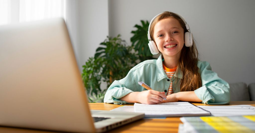 Niña feliz aprendiendo inglés en su laptop