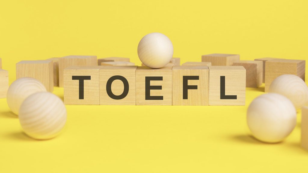 text toefl wooden cubes bright yellow surface wooden sphere balls among wood cubes different position niche market concept toefl test english as foreign language scaled - English4Kids